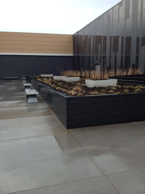 Norstone Lynia Interlocking Tiles in Ebony Basalt color on landscaping walls in a commercial project requiring durability and low maintenance